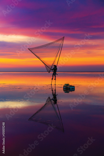 Silhouette of a man casting a net on the water in the sunset