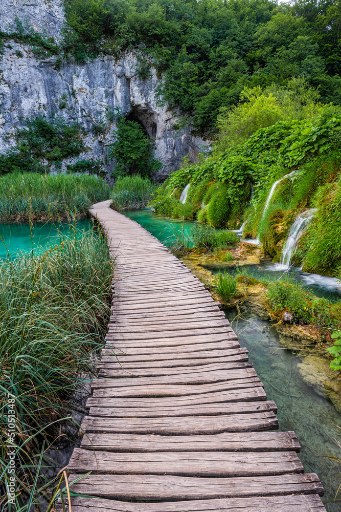 Plitvice, Croatia - Wooden walkway in Plitvice Lakes National Park on a bright summer day with crystal clear turquoise water, green summer foliage and small waterfalls