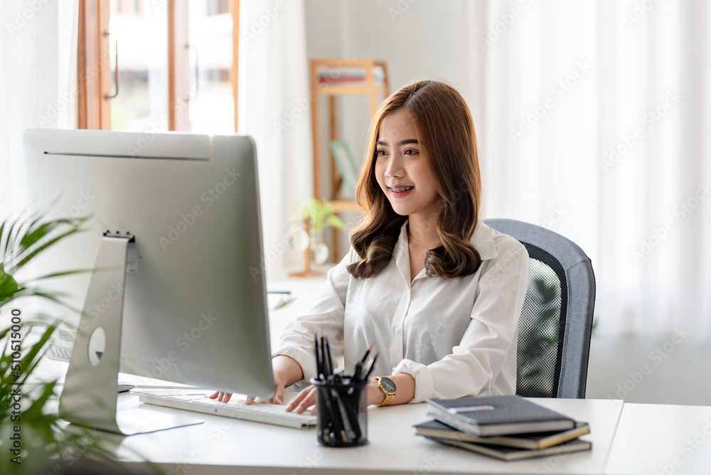 Portrait of young Asian business woman using laptop computer in the office.