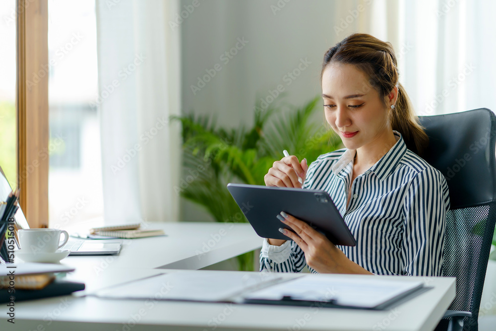 Portrait of young Asian business woman using digital tablet in the office.