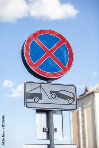 The road sign prohibits stopping against the background of buildings and cars. Close-up road signs No stopping and Tow Away Zone in city. Road signs of Stopping is prohibited 