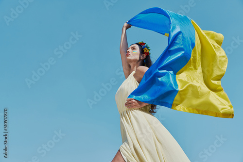 Confident Ukrainian woman carrying national flag with sky in the background