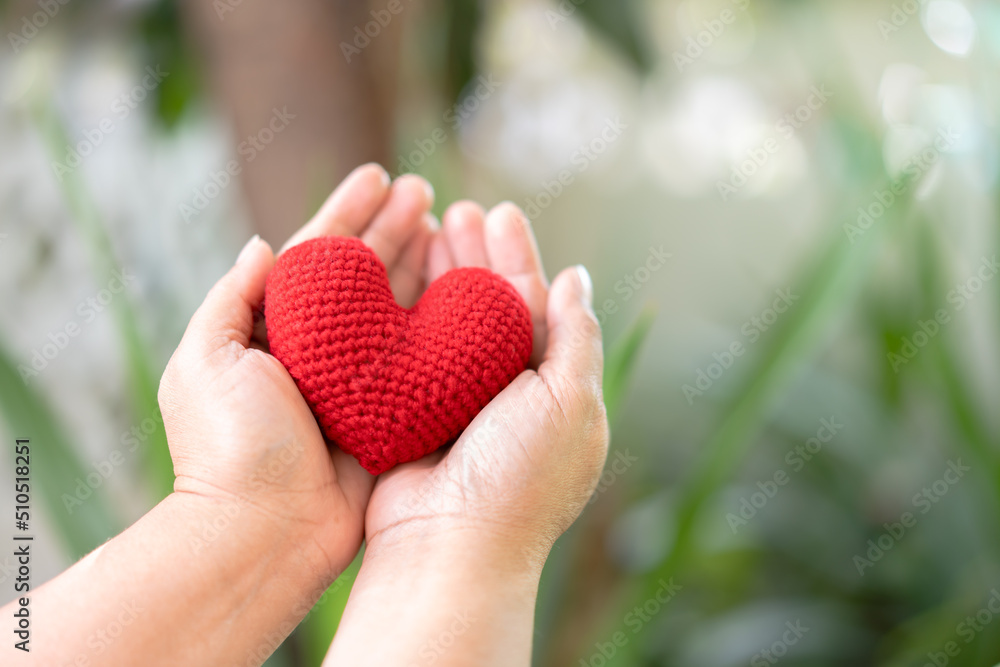Hand holding red yarn heart shape with natural beauty background in sunny day. Hand holding red yarn heart shape with natural beauty background in sunny day.