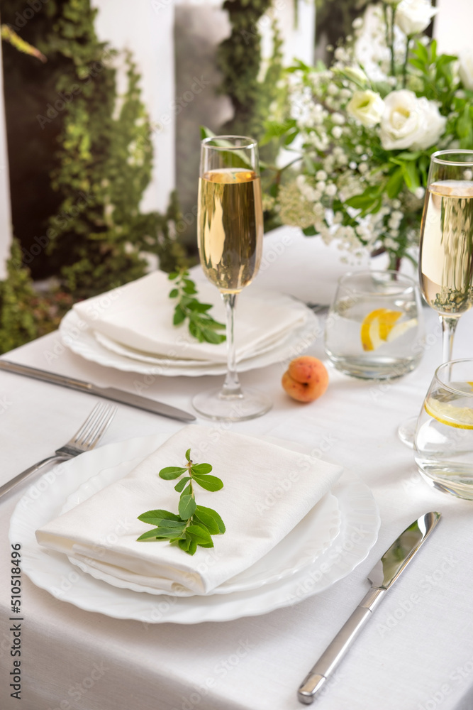 Fototapeta premium Wedding teble decoration with white flowers, glasses and white napkins. Elegantly decorated table at a wedding reception. Festive table setting. The wedding decor.