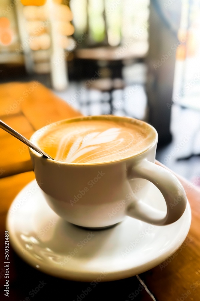 Close-up view of hot coffee latte with a cappuccino in a white cup on a wooden table with a vintage effect on wooden background in a coffee shop Close-up view of hot coffee latte with a cappuccino in a white cup on a wooden table with a vintage effect on wooden background in a coffee shop