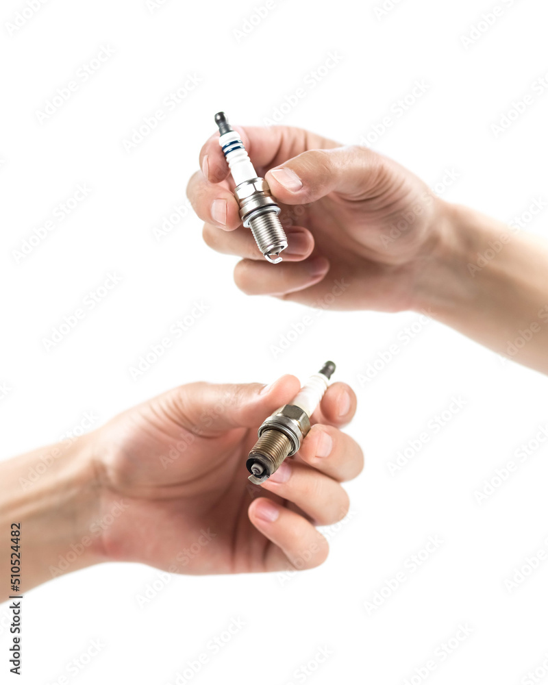 The hand holds a new and used iridium spark plugs. Close up. Isolated on a white background.
