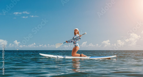 Healthy happy fit woman in bikini relaxing on a sup surfboard, floating on the clear turquoise sea water. Recreational Sports. Stand Up Paddle boarding. Summer fun, holidays travel. Active lifestyle © panophotograph