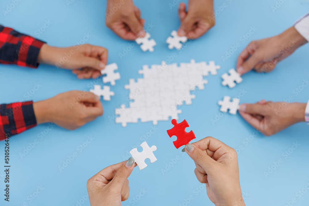 Hands of diverse people assembling jigsaw puzzle, team put pieces together searching for right match, help support in teamwork to find common solution concept, top close up view Hands of diverse people assembling jigsaw puzzle, team put pieces together searching for right match, help support in teamwork to find common solution concept, top close up view