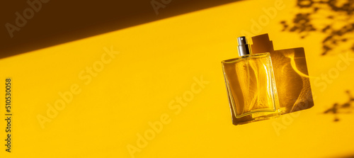 Transparent bottle of perfume on a yellow background. Fragrance presentation with daylight. Trending concept in natural materials with beautiful shadow. Women's essence. photo