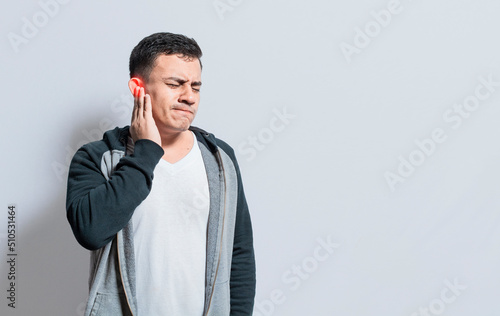 Person with ear pain, on isolated background, Suffering man massaging his ear isolated, A person with otitis and tinnitus photo