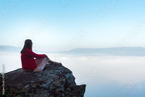 Traveler Asian woman enjoying and relaxing on the mountains view containing calm, fog, and mist in the morning. © May_Chanikran