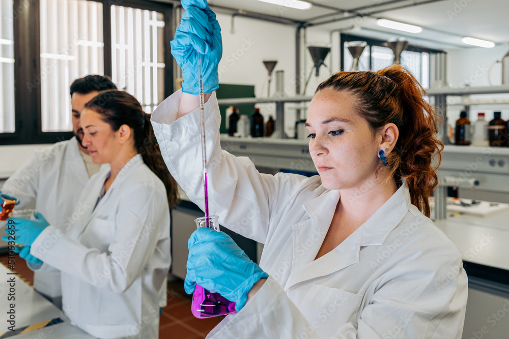 Chemist pouring liquid into flask in lab Chemist pouring liquid into flask in lab