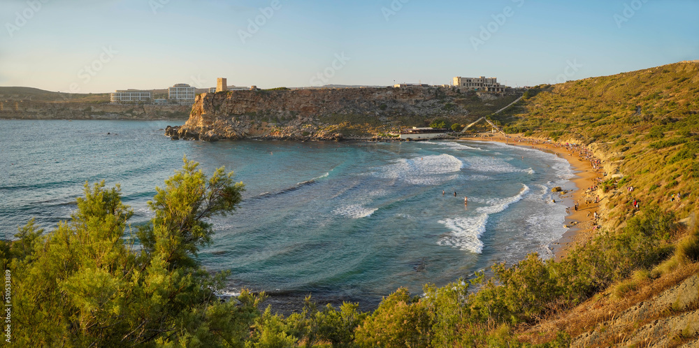 Panoramic view of a scenic beach (Ghajn Tuffieha) at sunset in Malta, June 2022. 