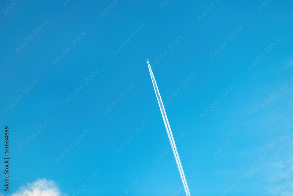 Airplane vapor trail or contrail pattern on blue sky with clouds Airplane vapor trail or contrail pattern on blue sky with clouds