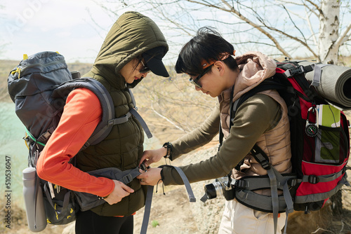 Papier peint Side view of young Asian woman hiking together with best friend or sister helpin