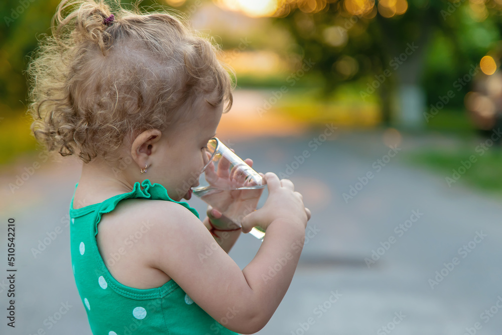 The child drinks water from a glass. Selective focus. The child drinks water from a glass. Selective focus.