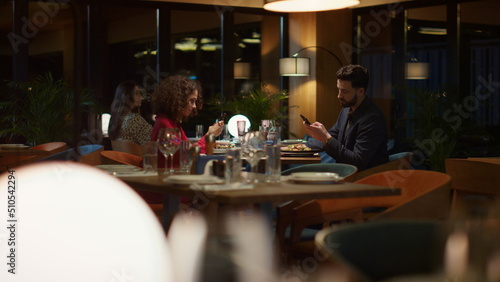 Busy couple texting phone mobile device on evening restaurant dinner date. 