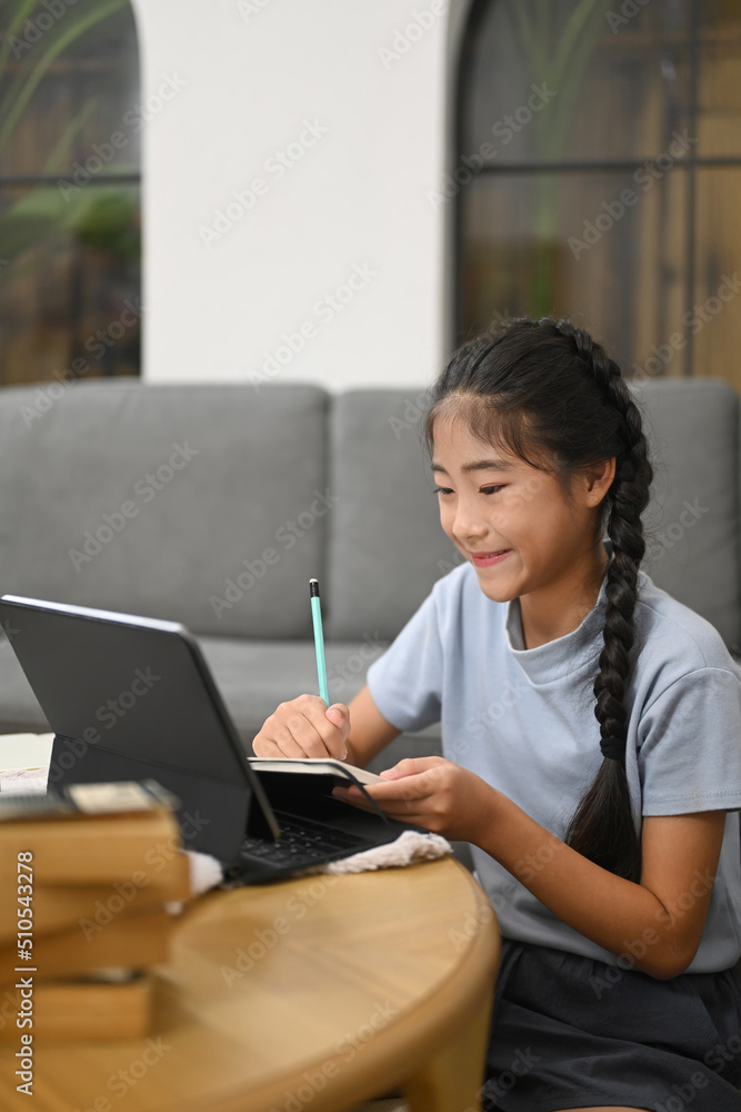 Smiling preteen girl having learning online at virtual class on laptop computer. Concept of Virtual education, homeschooling Smiling preteen girl having learning online at virtual class on laptop computer. Concept of Virtual education, homeschooling