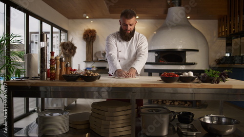 Fotografi Pastry cook hands knead pizza dough in restaurant kitchen