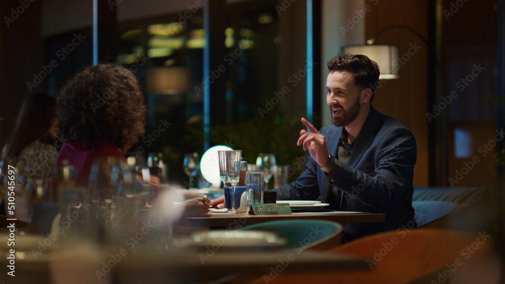 Multiethnic couple enjoying romantic dinner date in elegant night restaurant.