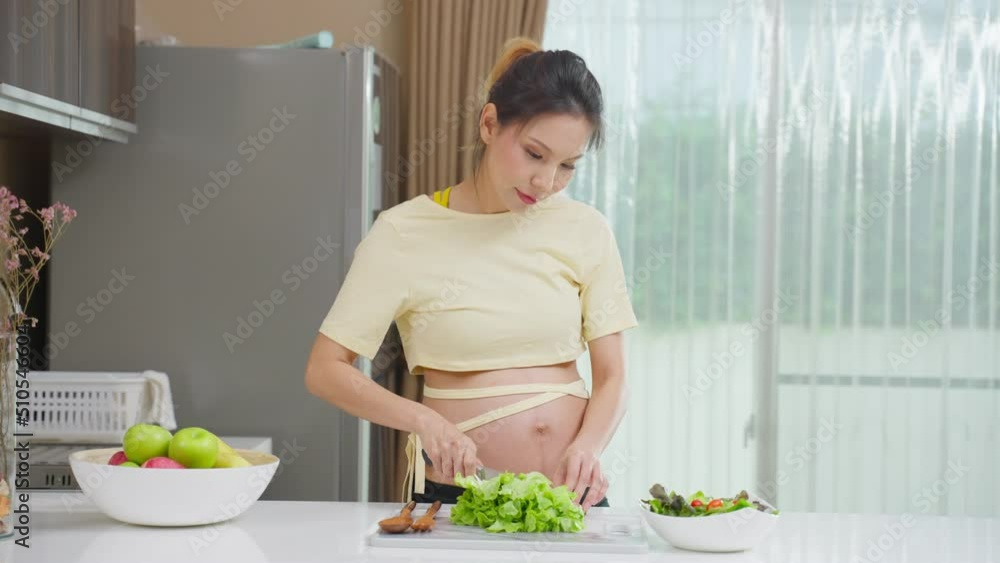 Asian beautiful pregnant woman cooking healthy food in kitchen at home. Asian beautiful pregnant woman cooking healthy food in kitchen at home.