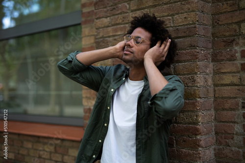 Handsome young man with headphones. Man listening the music while walking through the city..