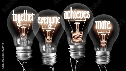 Light bulbs going from dark to light with Together Everyone Achieves More fiber text on black background. Concept of Team, Teamwork and Collaboration. High quality 4k video.