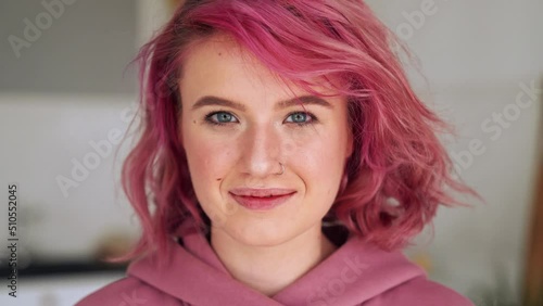 Happy teen girl with pink hair and nose piercing looking at camera. Close up portrait photo