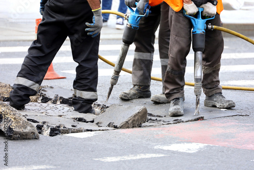 Workers repair the road surface with a jackhammer. Construction work, sewer repairing in city