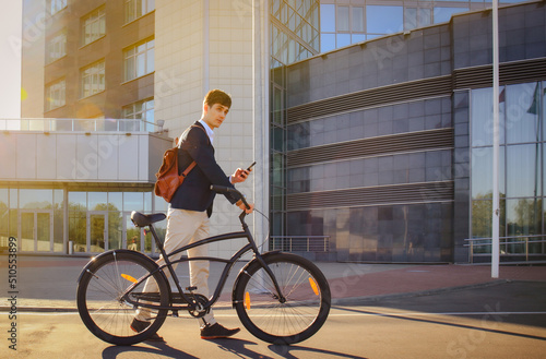 Confident young businessman walking with bicycle on the street in town photo