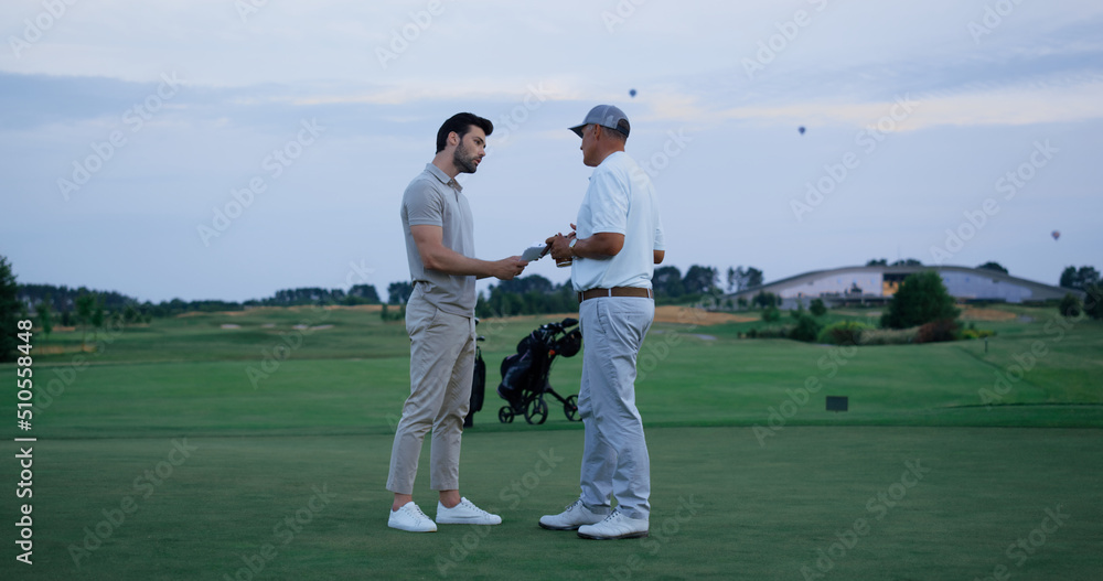Obraz premium Golf team fight together at green course. Two men argue at country club field
