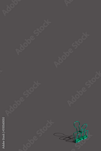 Flat lay composition with school green paper clip supplies on dark gray background. Vivid color minimal overhead shot with copy space. Back to school concept. Top view with sharp shadows.