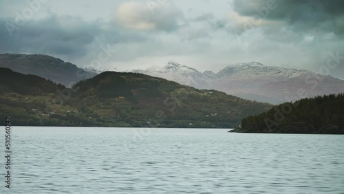 Sailing along the shores of the Hardanger fjord. Islands are scattered along the coast. Slow-motion, pan left. photo