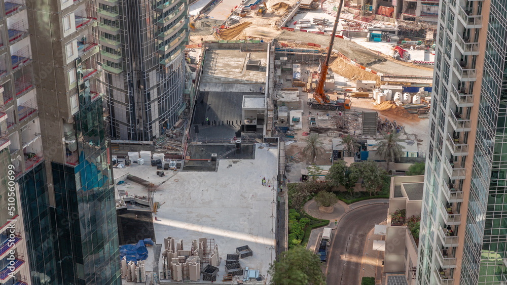 Obraz premium Crane and bulldozer working at construction site of new skyscraper aerial timelapse.