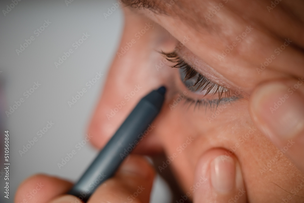 A woman appies eye liner to her eyes.