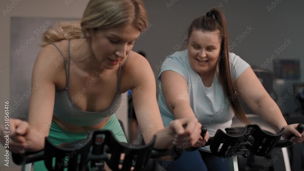 Two caucasian women ride a bikes at the gym. Shot with RED helium camera in 4K. Two caucasian women ride a bikes at the gym. Shot with RED helium camera in 4K.
