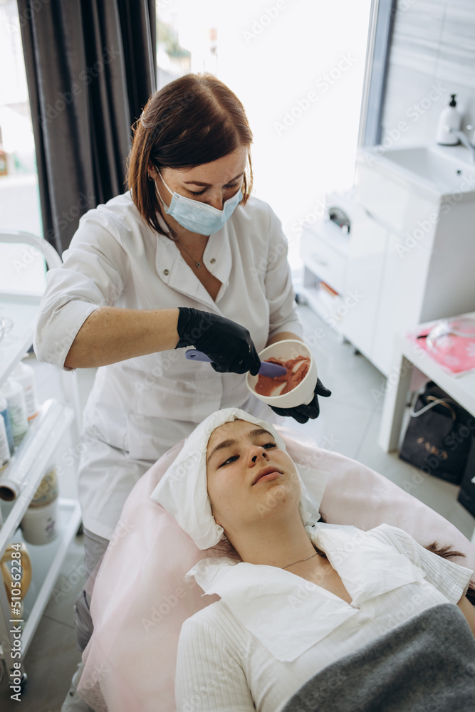 Aesthetic Procedure. Beautician Applying Clay Face Mask On Black Woman Face, Side View Aesthetic Procedure. Beautician Applying Clay Face Mask On Black Woman Face, Side View