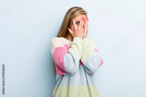 Fotografie young adult blonde pretty woman feeling scared or embarrassed, peeking or spying
