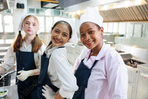 Group portrait young wman cooking student. Cooking class. culinary classroom. group of happy young woman multi - ethnic students are focusing on cooking lessons in a cooking school. photo