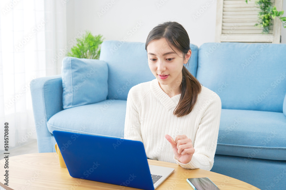 リビングでノートパソコンを見る女性 リビングでノートパソコンを見る女性