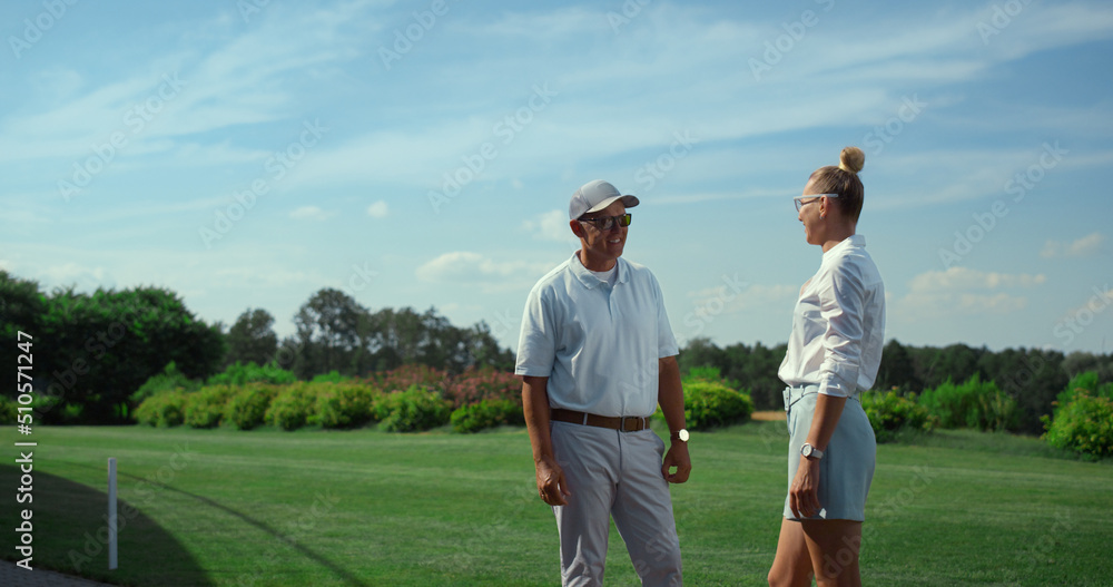 Two golfers talking sport on course field. Golf players chat on fairway grass.