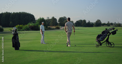 Active men enjoy golf on course field. Two golfers teeing play sport outside.