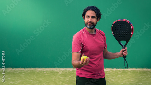 Monitor of padel holding black racket with yellow tennis ball in the hand.