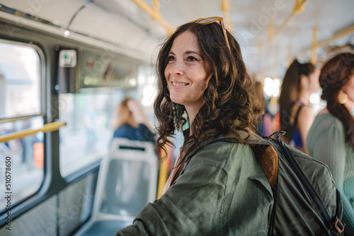 Foto Mid adult woman commuter is standing in bus and travelling in public transport