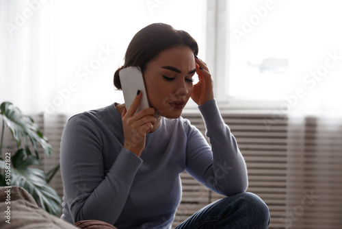 Portrait of upset young woman on the phone with a doctor receiving bad news. Sad female frowning, about to cry. Copy space for text, white wall background, close up.