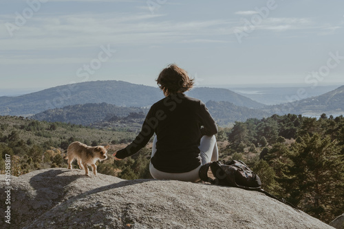 Young girl and her dog on a rock in the mountains, resting and looking at the scenery, in the Mountain Range of Madrid. photo