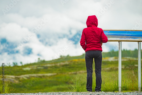 Tourist woman in mountains near information board. photo