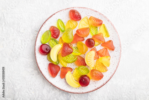 Various fruit candies on plate on gray concrete background. close up, top view.