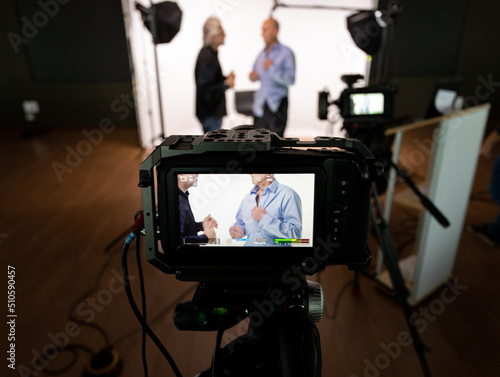 Studio for filming with two unrecognizable people framed in the camera preparing clothes.