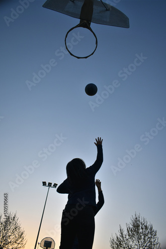 Silhouette of children playing basketball in the yard